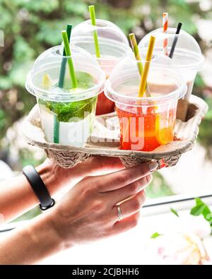 Varie bevande fredde estive e cocktail in un portaditumenti in mano alle donne Foto Stock