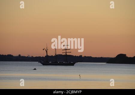 La vecchia nave a vela va al porto su un mare calmo in luce serale. Foto Stock