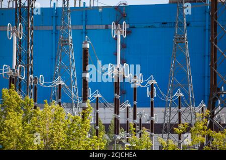 Centrale elettrica e apparecchiature ad alta tensione per sottostazioni trasformatrici su blu edificio di fabbrica sfondo Foto Stock
