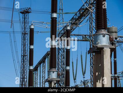 Sottostazione elettrica. Apparecchiature ad alta tensione, isolatori e griglie su cielo blu Foto Stock