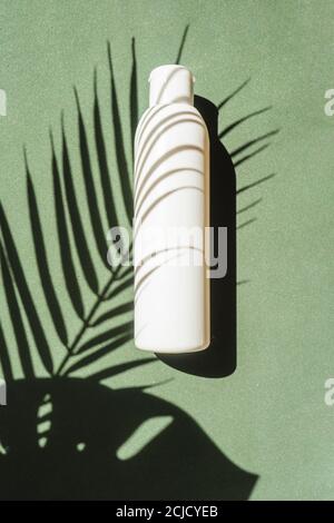 Scatto minimalistico creativo di un prodotto cosmetico. Concetto di spa. Impacchettamento cosmetico naturale biologico plastica mock up con ombra foglie tropicali. Foto Stock
