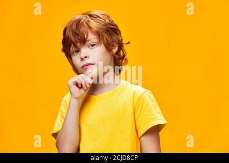 Il bambino dai capelli rossi con uno sguardo interessato tiene la sua mano Foto Stock