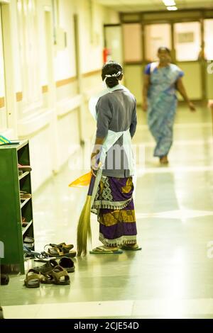 PUDUCHERRY, INDIA - MARZO CIRCA, 2020. Il personale pulisce il corridoio dell'ospedale per prevenire e uccidere i germi, con maschera facciale e scopa. Mancanza di prodotto Foto Stock