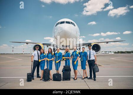 Lavoratori di linea aerea con valigie di viaggio in piedi all'aperto in campo aereo Foto Stock