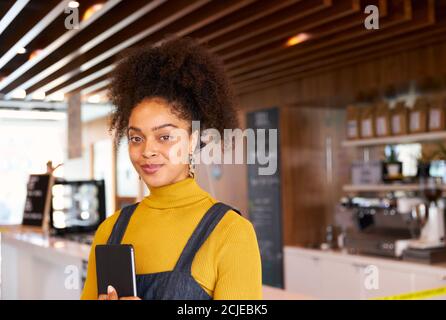 Ritratto di imprenditore femminile di caffetteria in maschera Utilizzo di Digital Tablet durante la pandemia di salute Foto Stock