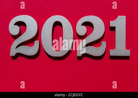 Fondo rosso anno nuovo con numeri in argento lucido 2021. Concetto minimalista su carta rossa con ombre dure. Foto Stock
