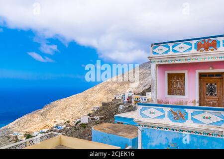 Olympos, Karpathos, Grecia - 9 settembre 2019: Casa rosa e blu su un pendio di montagna con vista sul Mar Egeo, casa tradizionale Foto Stock