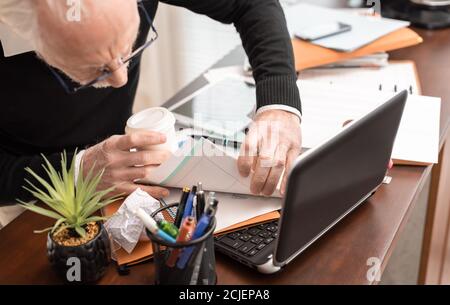 Uomo d'affari disorganizzato alla ricerca di documenti sulla sua scrivania Foto Stock