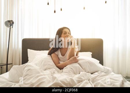 Donna dai capelli scuri e contenta avvolta in un piumino Foto Stock