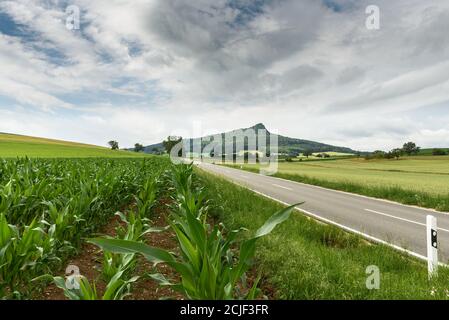 Strada di campagna nel paesaggio vulcanico Hegau, sulla destra il vulcano Hegau Hohenstoffeln, Baden-Wuerttemberg, Germania. Foto Stock