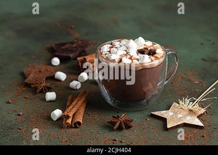 Cioccolata calda con marshmallow, anice, cannella e pezzi di cioccolato. Messa a fuoco selettiva, sfondo verde. Concetto di vacanza accogliente, Natale Foto Stock