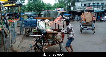 DISTRETTO KATNI, INDIA - 12 AGOSTO 2019: Un rider asiatico di risciò che carica le borse di verdure su strada da sforzi di auto. Foto Stock