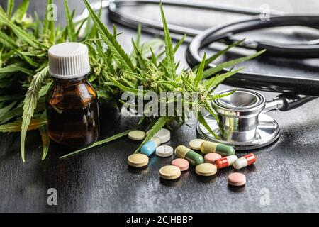 Boccioli di marijuana fiori di cannabis, stetoscopio, pillole e olio su tavola nera. Foto Stock