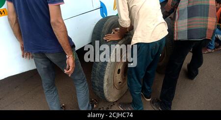 DISTRETTO KATNI, INDIA - 17 AGOSTO 2019: Lavoratore di automobile asiatico che cambia la gomma dell'autobus sulla strada durante il trasporto all'autostrada nazionale di Jabalpur. Foto Stock