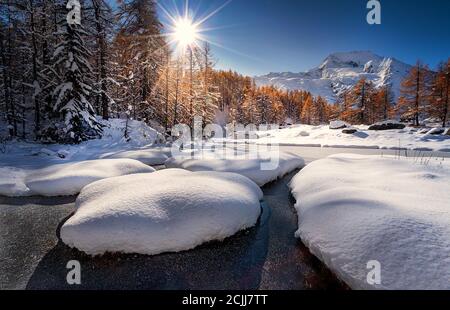 Montagna innevata nelle Alpi francesi. Cielo blu con il sole. Nevicate in autunno con alberi marroni Foto Stock