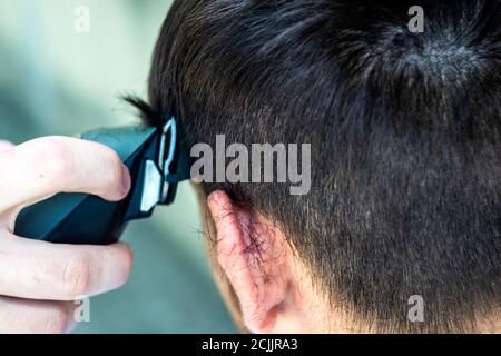 il barbiere taglia il ragazzo con un regolacapelli Foto Stock