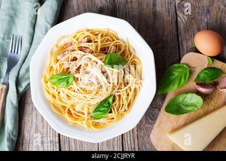 Pasta italiana carbonara a base di uova, formaggi stagionati, guanciale di maiale o pancetta e pepe nero. Cibo tipico in Italia, piatto, backgro rustico Foto Stock