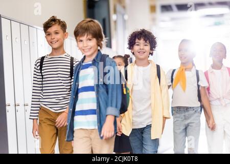 fuoco selettivo dei compagni multiculturali che camminano lungo il corridoio nella scuola Foto Stock