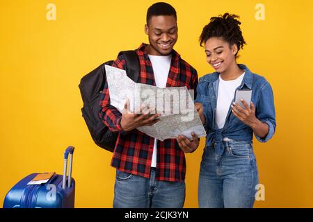 Coppia che sceglie destinazione di viaggio con smartphone e mappa in Studio Foto Stock