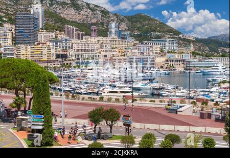 Monte Carlo, Monaco - 15 agosto 2018: Vista sul porto di Hercule nella soleggiata giornata estiva. I turisti camminano per la strada Foto Stock