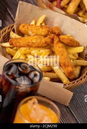 Le dita di pollo speziate e le patatine fritte con la cola di ghiaccio Foto Stock
