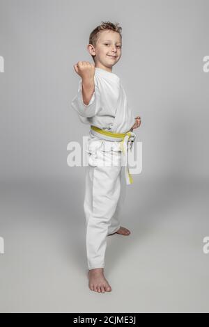 bambino sorridente che pratica arti marziali indossando un judogi. Foto Stock