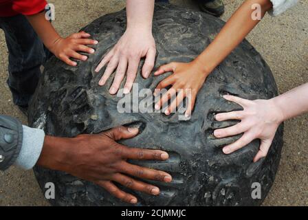 Mani multiple di razze diverse si inseriscono nelle stampe a mano su un pezzo di arte moderna. Immagine concettuale multiculturale Foto Stock