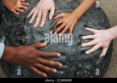 Mani multiple di razze diverse si inseriscono nelle stampe a mano su un pezzo di arte moderna. Immagine concettuale multiculturale Foto Stock