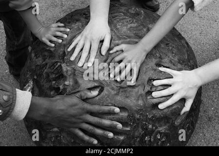 Mani multiple di razze diverse si inseriscono nelle stampe a mano su un pezzo di arte moderna. Immagine concettuale multiculturale. Versioni in bianco e nero. Foto Stock