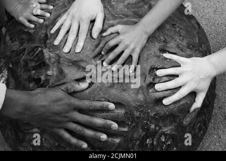 Mani multiple di razze diverse si inseriscono nelle stampe a mano su un pezzo di arte moderna. Immagine concettuale multiculturale. Versioni in bianco e nero. Foto Stock