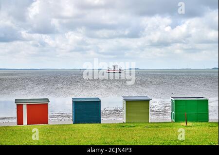 Vista sulle colorate bancarelle della spiaggia al watt con un traghetto Foto Stock