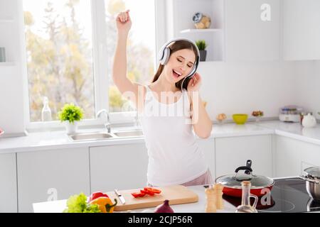 Foto di un allegro piatto da donna che cucina con una danza di pomodoro  fresco con un'energica cuffia melodia in cucina Foto stock - Alamy