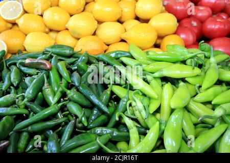 Peperoncini verdi caldi, limoni gialli e pomodori rossi in luce naturale. Modello di cibo colorato. Foto Stock