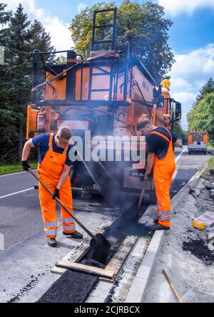 09 settembre 2020, Meclemburgo-Pomerania occidentale, Gnoien: I tirocinanti Ole Wittke (r) e Tom Sievert (l) stanno lavorando ad una fermata dell'autobus e stanno applicando una nuova superficie stradale. I futuri addetti alla manutenzione stradale del Meclemburgo-Vorpommern sono addestrati al Straßenmeisterei Teterow. Il reparto di manutenzione stradale è responsabile di circa 200 chilometri di strade statali e federali. Foto: Jens Büttner/dpa-Zentralbild/ZB Foto Stock