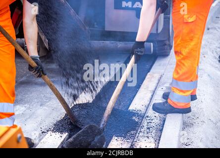 09 settembre 2020, Meclemburgo-Pomerania occidentale, Gnoien: I tirocinanti Ole Wittke (r) e Tom Sievert (l) stanno lavorando ad una fermata dell'autobus e stanno applicando una nuova superficie stradale. I futuri addetti alla manutenzione stradale del Meclemburgo-Vorpommern sono addestrati al Straßenmeisterei Teterow. Il reparto di manutenzione stradale è responsabile di circa 200 chilometri di strade statali e federali. Foto: Jens Büttner/dpa-Zentralbild/ZB Foto Stock