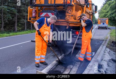 09 settembre 2020, Meclemburgo-Pomerania occidentale, Gnoien: I tirocinanti Ole Wittke (r) e Tom Sievert (l) stanno lavorando ad una fermata dell'autobus e stanno applicando una nuova superficie stradale. I futuri addetti alla manutenzione stradale del Meclemburgo-Vorpommern sono addestrati al Straßenmeisterei Teterow. Il reparto di manutenzione stradale è responsabile di circa 200 chilometri di strade statali e federali. Foto: Jens Büttner/dpa-Zentralbild/ZB Foto Stock