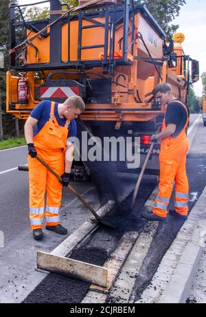 09 settembre 2020, Meclemburgo-Pomerania occidentale, Gnoien: I tirocinanti Ole Wittke (r) e Tom Sievert (l) stanno lavorando ad una fermata dell'autobus e stanno applicando una nuova superficie stradale. I futuri addetti alla manutenzione stradale del Meclemburgo-Vorpommern sono addestrati al Straßenmeisterei Teterow. Il reparto di manutenzione stradale è responsabile di circa 200 chilometri di strade statali e federali. Foto: Jens Büttner/dpa-Zentralbild/ZB Foto Stock