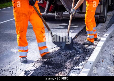 09 settembre 2020, Meclemburgo-Pomerania occidentale, Gnoien: I tirocinanti Ole Wittke (r) e Tom Sievert (l) stanno lavorando ad una fermata dell'autobus e stanno applicando una nuova superficie stradale. I futuri addetti alla manutenzione stradale del Meclemburgo-Vorpommern sono addestrati al Straßenmeisterei Teterow. Il reparto di manutenzione stradale è responsabile di circa 200 chilometri di strade statali e federali. Foto: Jens Büttner/dpa-Zentralbild/ZB Foto Stock