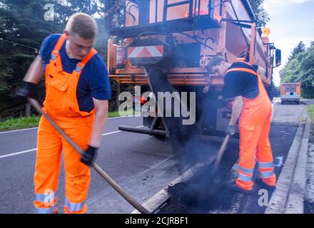 09 settembre 2020, Meclemburgo-Pomerania occidentale, Gnoien: I tirocinanti Ole Wittke (r) e Tom Sievert (l) stanno lavorando ad una fermata dell'autobus e stanno applicando una nuova superficie stradale. I futuri addetti alla manutenzione stradale del Meclemburgo-Vorpommern sono addestrati al Straßenmeisterei Teterow. Il reparto di manutenzione stradale è responsabile di circa 200 chilometri di strade statali e federali. Foto: Jens Büttner/dpa-Zentralbild/ZB Foto Stock