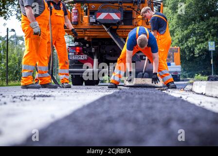 09 settembre 2020, Meclemburgo-Pomerania occidentale, Gnoien: I tirocinanti Ole Wittke (r) e Tom Sievert (l) stanno lavorando ad una fermata dell'autobus e stanno applicando una nuova superficie stradale. I futuri addetti alla manutenzione stradale del Meclemburgo-Vorpommern sono addestrati al Straßenmeisterei Teterow. Il reparto di manutenzione stradale è responsabile di circa 200 chilometri di strade statali e federali. Foto: Jens Büttner/dpa-Zentralbild/ZB Foto Stock