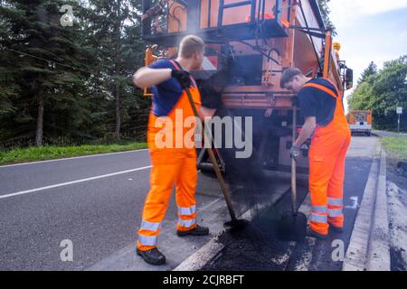 09 settembre 2020, Meclemburgo-Pomerania occidentale, Gnoien: I tirocinanti Ole Wittke (r) e Tom Sievert (l) stanno lavorando ad una fermata dell'autobus e stanno applicando una nuova superficie stradale. I futuri addetti alla manutenzione stradale del Meclemburgo-Vorpommern sono addestrati al Straßenmeisterei Teterow. Il reparto di manutenzione stradale è responsabile di circa 200 chilometri di strade statali e federali. Foto: Jens Büttner/dpa-Zentralbild/ZB Foto Stock