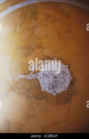 Tondo decorativo stucco rilievo stampaggio con ornamenti floreali sul vecchio soffitto . Casa infestata di concetto interno. Foto Stock