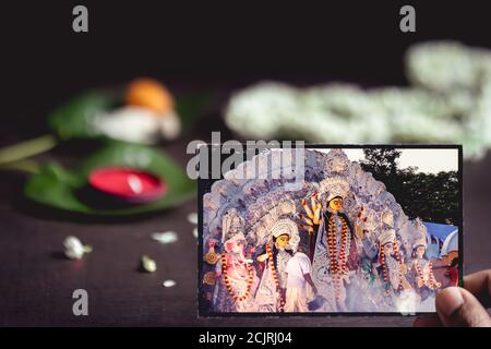 Durga Puja o Pooja immagine di sfondo con spazio di copia. Vecchia fotografia della dea indiana Durga con fiori, kumkum, foglie di betel per i rituali. Foto Stock