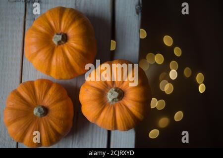 tre piccole zucche su un tavolo di legno con luce bokeh gialla Foto Stock