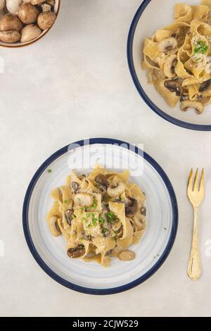 Fettuccine italiane fatte in casa con funghi e parmigiano (fettuccine al Fungi Porcini). Cucina tradizionale italiana. Servita su sfondo bianco. Foto Stock