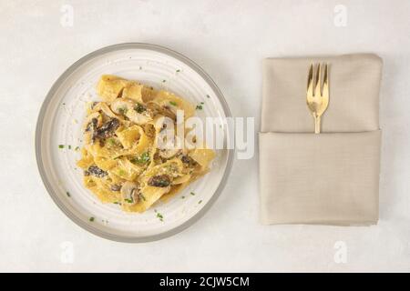 Fettuccine italiane fatte in casa con funghi e parmigiano (fettuccine al Fungi Porcini). Cucina tradizionale italiana. Servita su sfondo bianco. Foto Stock