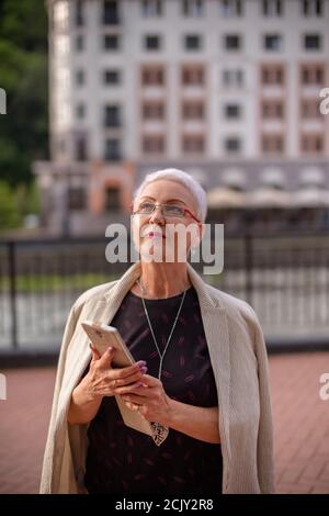 una piacevole donna d'affari sta guardando la parte superiore del grattacielo. primo piano della foto Foto Stock