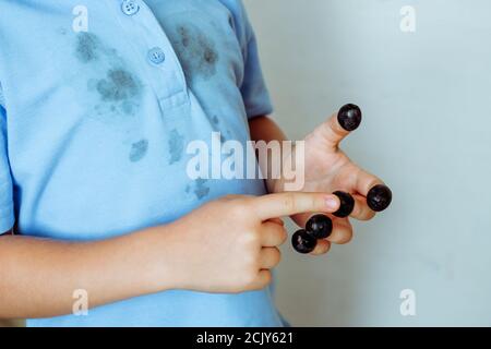 Olive nere su ogni dito della mano di un bambino e conta lo sfondo delle macchie su una T-shirt. Isolato su sfondo bianco Foto Stock