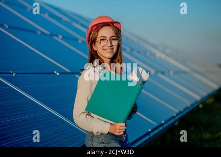 Ingegnere in arancione casco sorridente e tenere cartella, Green Energy Concept. Foto Stock