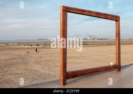 Zeebrugge, Belgio - 31 ottobre 2019: Opere d'arte in legno sulla spiaggia di Zeebrugge che incorniciano le gru lontane del porto internazionale Foto Stock